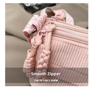 Detailed macro view of smooth pink corduroy fabric and durable zippers on the crossbody bag