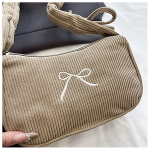 Close-up of khaki corduroy shoulder bag showing bow embroidery and ribbed texture