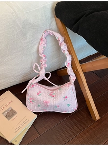Detail of pink floral underarm bag featuring rose patterns and a ruched cloud strap