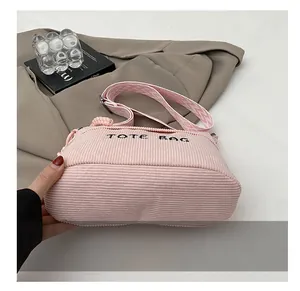 Detailed close-up of pink corduroy tote bag featuring black embroidery and woven strap