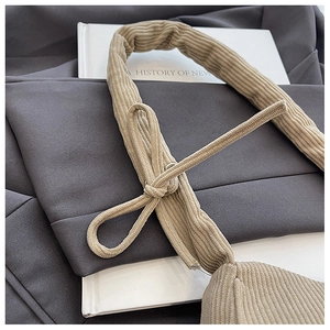 Detail of light brown corduroy tote bag showing wide handle and texture on book background
