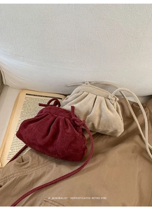 Detail of retro pleated drawstring cloud bags in burgundy and off-white suede texture