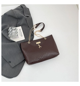 Detail of dark brown tote with woven leather texture, gold chain strap and deer charm