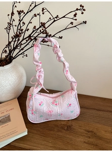 Detail of pink floral quilted bag featuring rose prints and ruched handle design