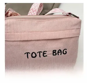 Detailed close-up of pink corduroy tote bag featuring embroidery and woven strap texture