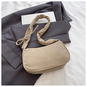 Detail of beige corduroy underarm bag featuring a ruched strap and metal ring attachment