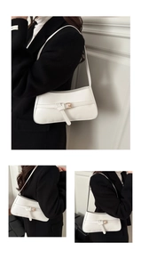 Detail of white PU shoulder bag featuring gold buckle strap and sleek minimalist design