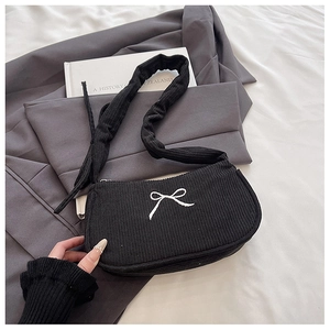 Detail of black corduroy shoulder bag featuring white bow embroidery and ruched strap