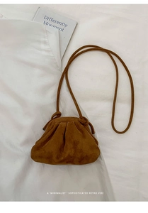 Brown faux suede pleated dumpling bag with thin strap on minimalist white bedding