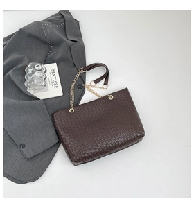 Detail of dark brown woven texture tote bag with gold chain strap and luxury finish