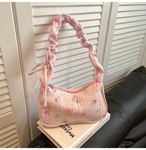 Detail of pink floral handbag showing ruffled shoulder strap and bow decoration