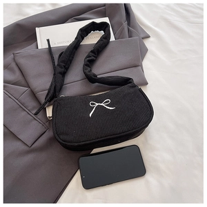 Detail of black corduroy shoulder bag with white bow embroidery and ruffled strap