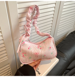 Close-up of pink floral underarm bag featuring rose patterns and a scrunchie strap