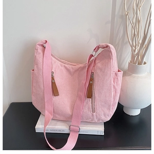 Pink corduroy crossbody bag detail showing vertical zip pockets and leather pullers