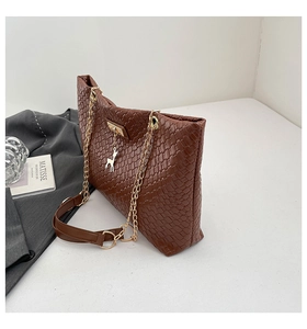 Detail of a brown woven PU leather tote bag featuring gold chain straps and deer charm