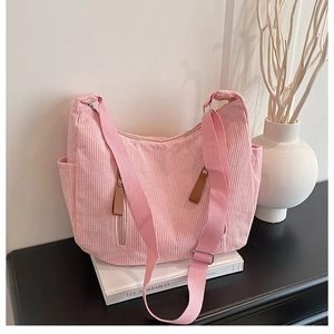 Detailed close-up of pink corduroy shoulder bag showing texture, side pocket and metal strap buckle