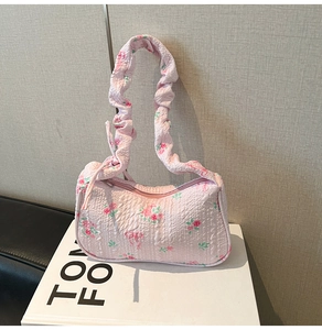 Detailed close-up of pink floral underarm bag with ruffled strap and seersucker texture