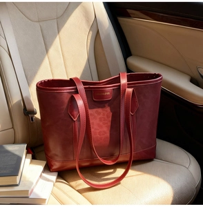 Vue détaillée du sac cabas rouge foncé en cuir avec plaque de marque dorée