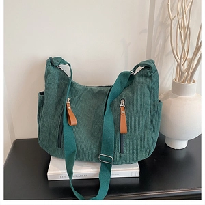 Detail of dark green corduroy crossbody bag with double vertical zipper pockets and leather pulls