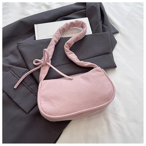 Detailed close-up of pink corduroy shoulder bag with elegant bow knot on the strap