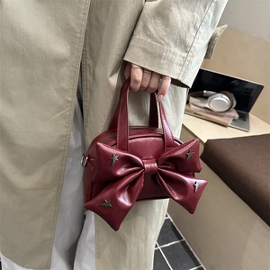 Burgundy bucket bag featuring a large bow and star studs with a top handle and chain