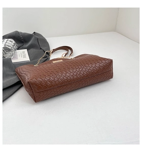 Detail of brown woven faux leather handbag with gold metal chain and textured finish