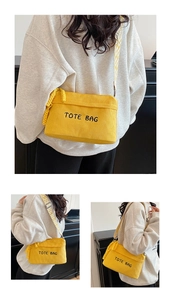 Detail of yellow corduroy tote bag with embroidered text and geometric patterned shoulder strap
