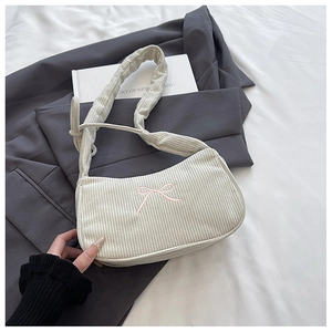 Detailed texture of off-white corduroy shoulder bag with pink embroidered bow and pleated strap