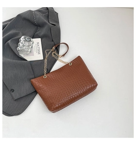 Detailed view of brown woven texture tote bag with gold chain and leather shoulder strap
