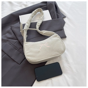 Detail of beige corduroy shoulder bag featuring an embroidered pink ribbon on texture