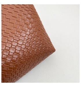 Close-up of brown woven leather texture on a stylish minimalist shoulder tote bag