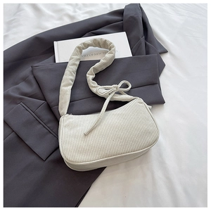 Detailed texture of off-white corduroy baguette bag with decorative side knot and soft strap