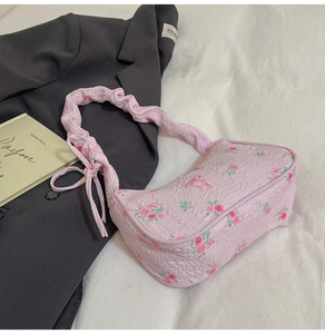 Detailed close-up of pink seersucker shoulder bag with floral pattern and ruched strap