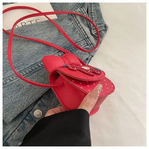 Detail of red mini crossbody bag for girls featuring a 3D bow and heart polka dot pattern