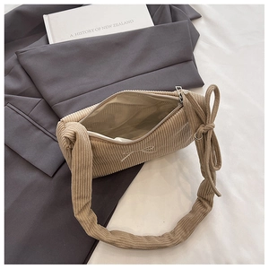 Detail of beige corduroy shoulder bag showing vertical texture and bow knot strap