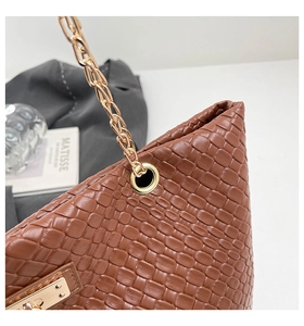 Detail of brown woven texture tote bag featuring golden metal chain strap and lock
