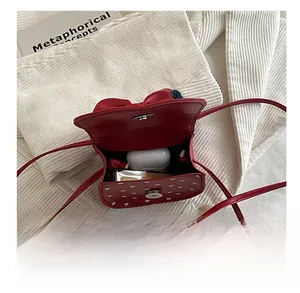 Nahaufnahme der roten Mini-Tasche mit Punkten zeigt Platz für Kopfhörer und Lippenstift