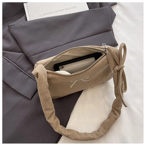 Detail of corduroy handbag with embroidered bow showing interior storage and knot handle