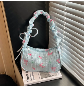 Detail of light blue floral fabric texture and cloud-style pleated bow shoulder strap