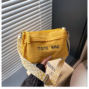 Detail of yellow corduroy tote bag featuring embroidery and checkered wide strap
