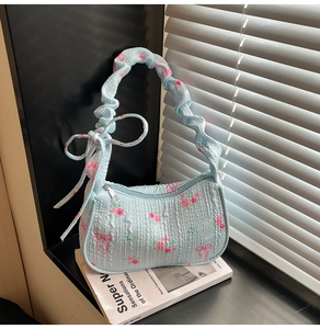 Detail of light blue seersucker texture with pink rose floral and bow design on the bag