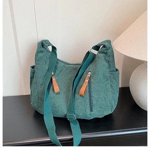 Close-up of green corduroy dumpling bag with double zippers and wide adjustable strap