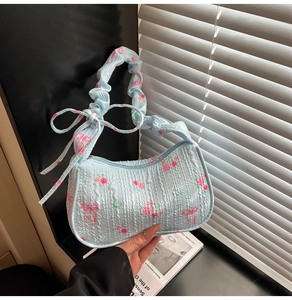 Close-up of light blue bubble textured handbag with rose patterns and bow details