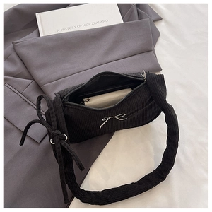 Detail of black corduroy shoulder bag with bow, showing interior wallet storage and zipper