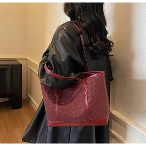 Detailed view of large dark red leopard print tote bag worn on shoulder by a model