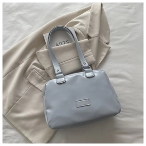 Detail of light blue faux leather shoulder bag with smooth texture and rectangle tag