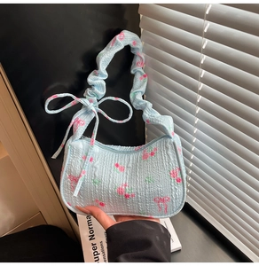 Detail of light blue pleated handbag featuring pink rose floral and bow patterns