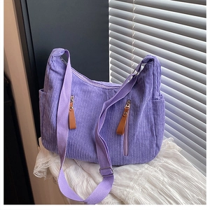 Close-up of purple corduroy hobo bag featuring vertical zipper pockets and brown leather pulls