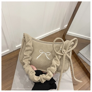 Detail of corduroy shoulder bag with embroidered bow and cloud-shaped pleated strap