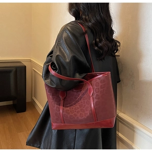 Détail d'un sac cabas léopard bordeaux porté avec une veste en cuir noir élégante